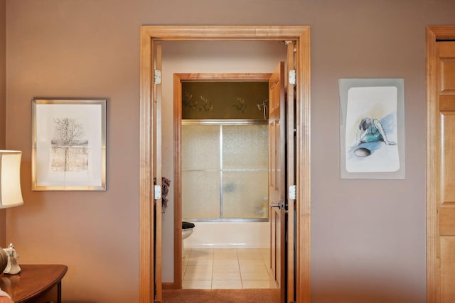 bathroom featuring tile patterned flooring, combined bath / shower with glass door, and toilet