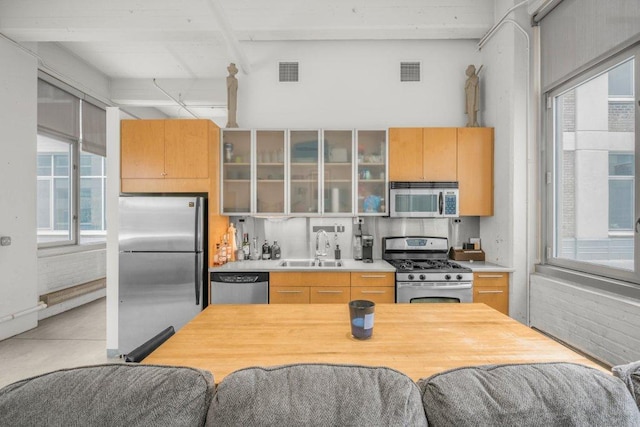 kitchen featuring stainless steel appliances, beamed ceiling, light brown cabinetry, and sink