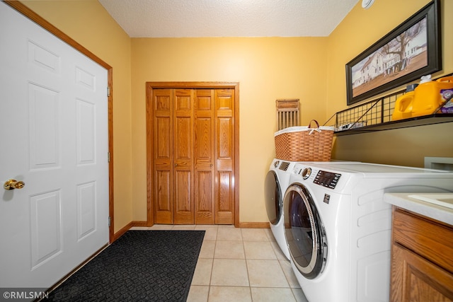 clothes washing area with washer and clothes dryer, light tile patterned floors, and a textured ceiling