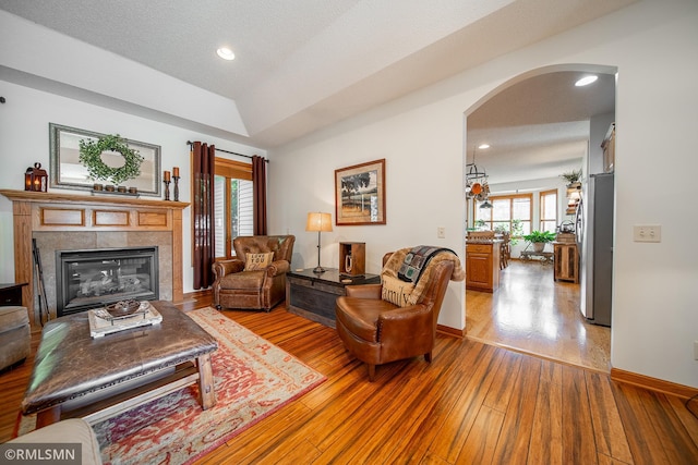 living room featuring a textured ceiling, light wood-type flooring, and a fireplace