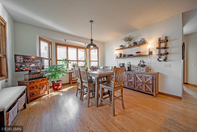 dining space with a textured ceiling and light hardwood / wood-style floors