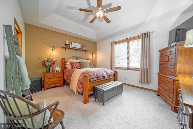 bedroom featuring light carpet, a tray ceiling, and ceiling fan