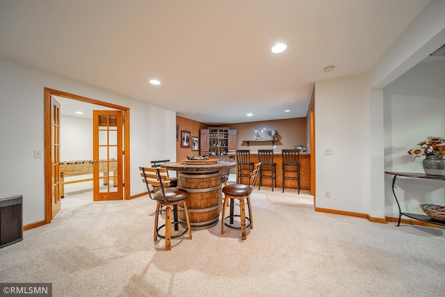 dining area featuring light carpet, bar, and french doors