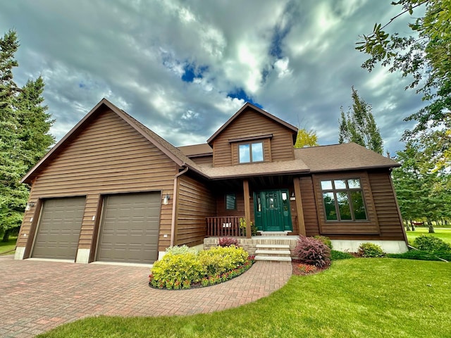 312 Oakdale Ct NE, Warroad, MN 56763 - view of front facade with decorative driveway, covered porch, an attached garage, a front yard, and roof with shingles