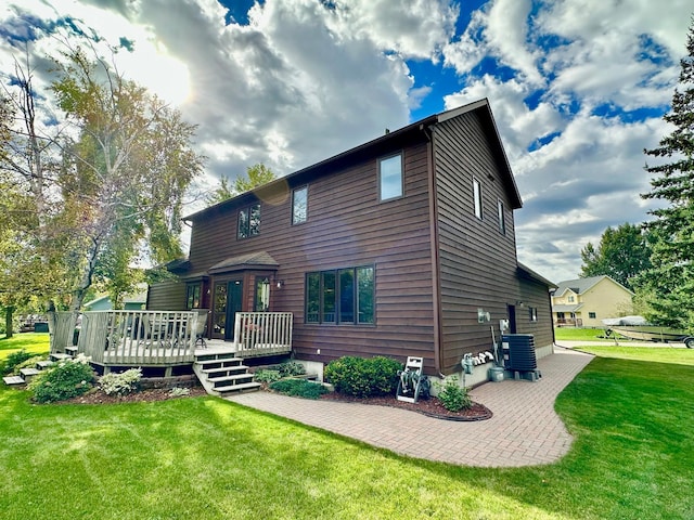 rear view of house featuring central AC unit, a lawn, and a wooden deck