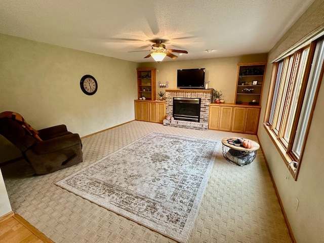 living room with a textured ceiling, a brick fireplace, and ceiling fan