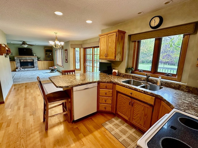 kitchen with dishwasher, sink, kitchen peninsula, stove, and pendant lighting