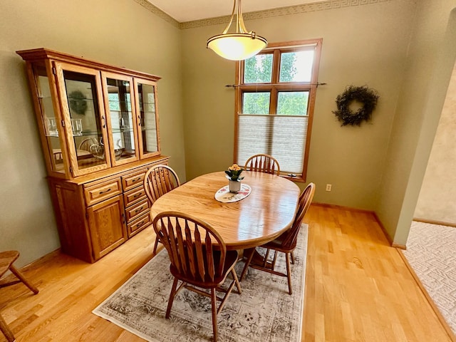 dining area featuring light wood-type flooring and ornamental molding