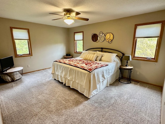 carpeted bedroom featuring multiple windows, ceiling fan, and a textured ceiling