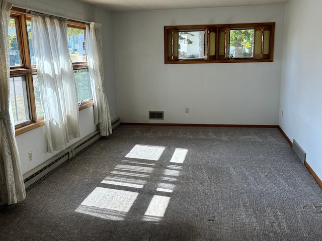 empty room with baseboard heating and dark colored carpet