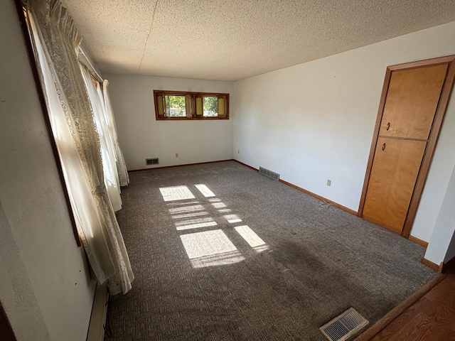 unfurnished bedroom with dark colored carpet and a textured ceiling