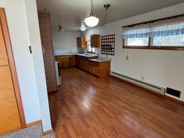 kitchen with baseboard heating, dark hardwood / wood-style floors, decorative light fixtures, and sink