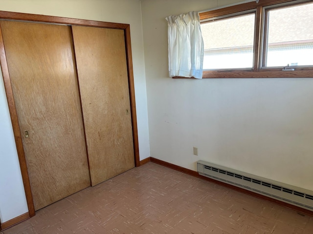 unfurnished bedroom featuring baseboard heating and a closet