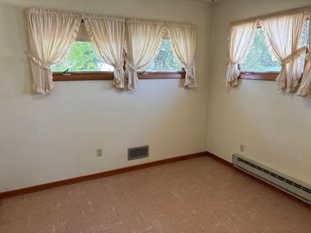 unfurnished room with baseboard heating and a wealth of natural light