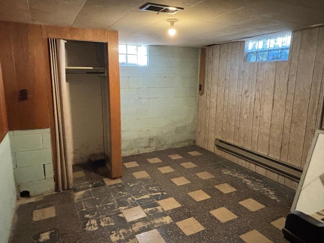 basement with wooden walls and a baseboard heating unit