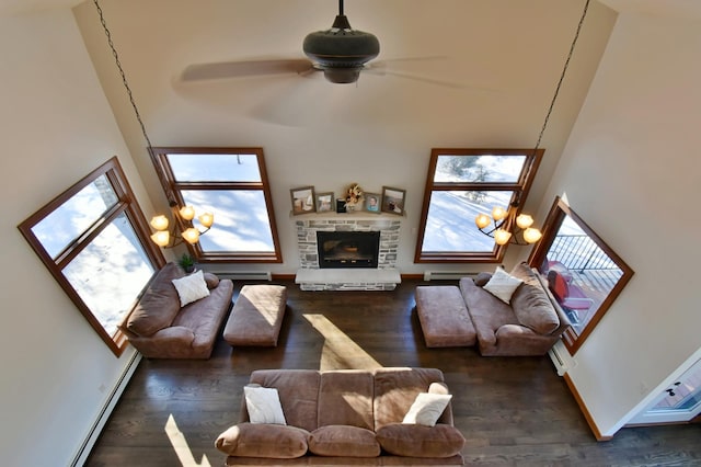 living room featuring a towering ceiling, a baseboard heating unit, a fireplace, and dark hardwood / wood-style floors