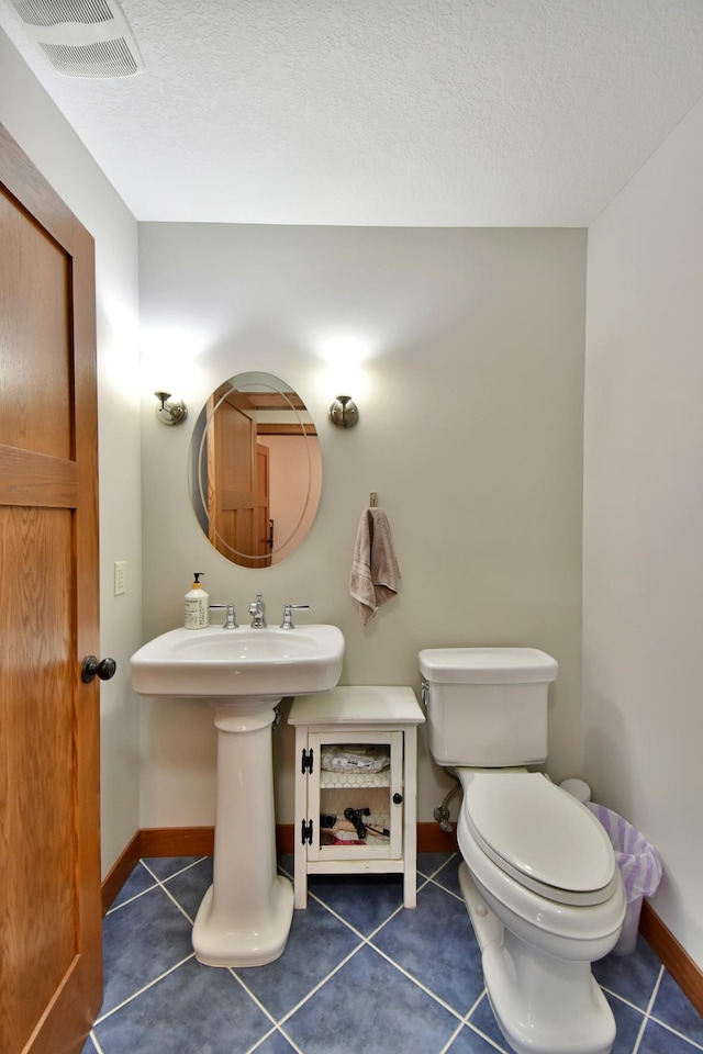 bathroom with toilet, tile patterned flooring, and a textured ceiling