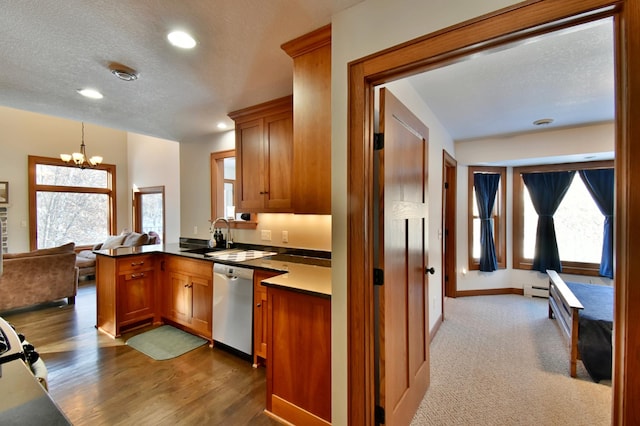 kitchen with kitchen peninsula, dishwasher, a chandelier, hanging light fixtures, and sink