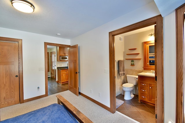 bedroom featuring ensuite bathroom, dark tile patterned floors, and sink