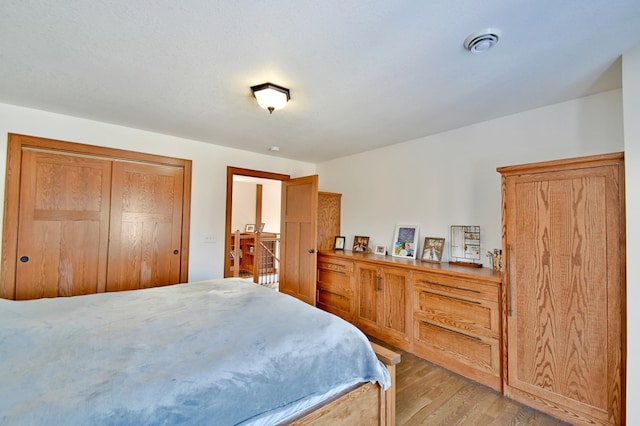 bedroom with light hardwood / wood-style floors and a closet