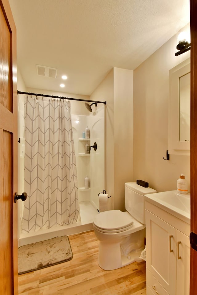 bathroom featuring curtained shower, vanity, toilet, and hardwood / wood-style floors