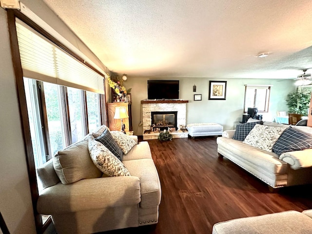 living room featuring a fireplace, ceiling fan, dark hardwood / wood-style floors, and a textured ceiling