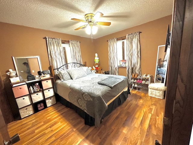 bedroom featuring ceiling fan, hardwood / wood-style flooring, and a textured ceiling