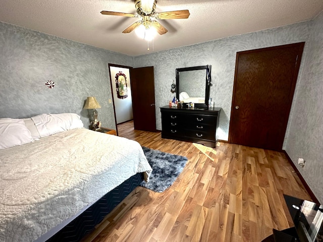 bedroom with light wood-type flooring, ceiling fan, and a textured ceiling