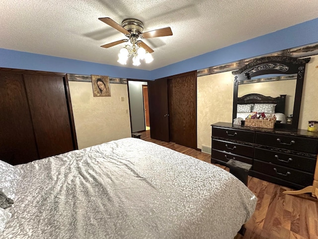 bedroom with ceiling fan, a textured ceiling, and dark wood-type flooring