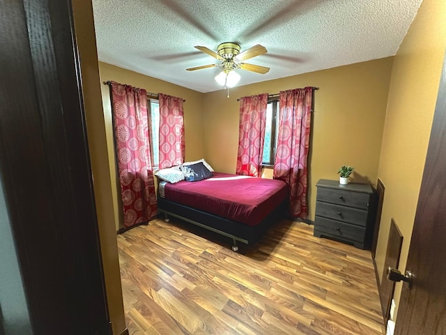 bedroom with ceiling fan, a textured ceiling, and light hardwood / wood-style floors