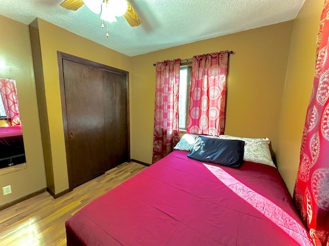 bedroom featuring a textured ceiling, a closet, light wood-type flooring, and ceiling fan