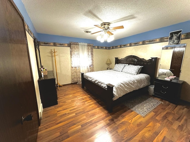 bedroom with ceiling fan, a textured ceiling, and dark hardwood / wood-style flooring