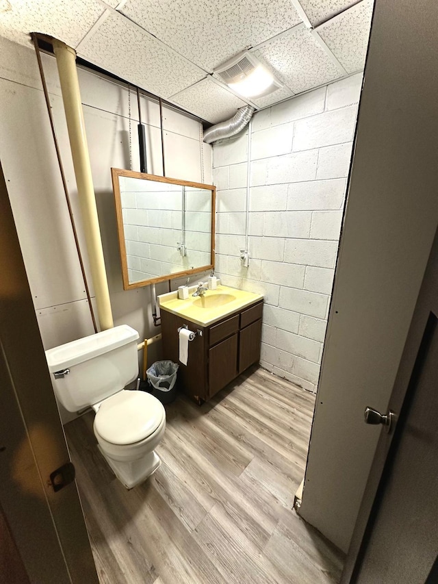 bathroom featuring a drop ceiling, toilet, hardwood / wood-style floors, and vanity