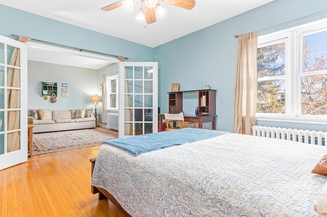 bedroom featuring french doors, ceiling fan, wood-type flooring, and radiator