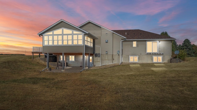 back house at dusk with a patio and a lawn