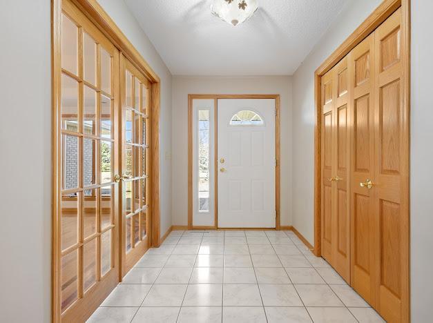 entryway featuring french doors, light tile patterned flooring, and a textured ceiling