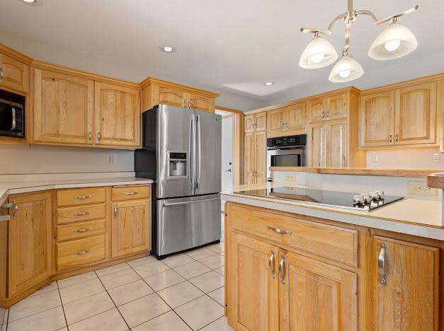 kitchen featuring stainless steel appliances, light tile patterned flooring, pendant lighting, and an inviting chandelier