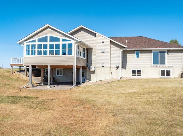 rear view of property featuring a patio area, a yard, and a sunroom