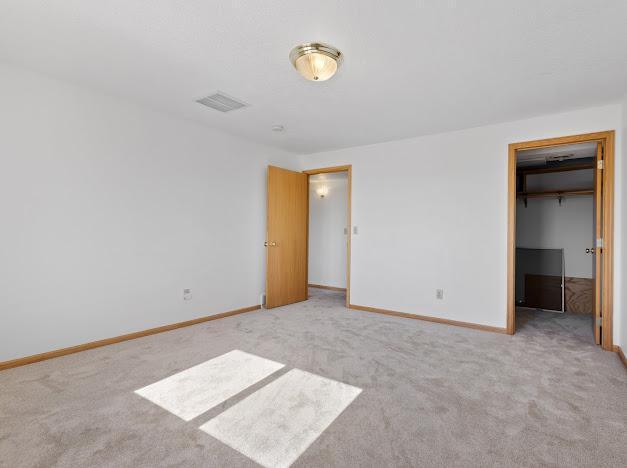 unfurnished bedroom featuring a spacious closet, light carpet, and a closet