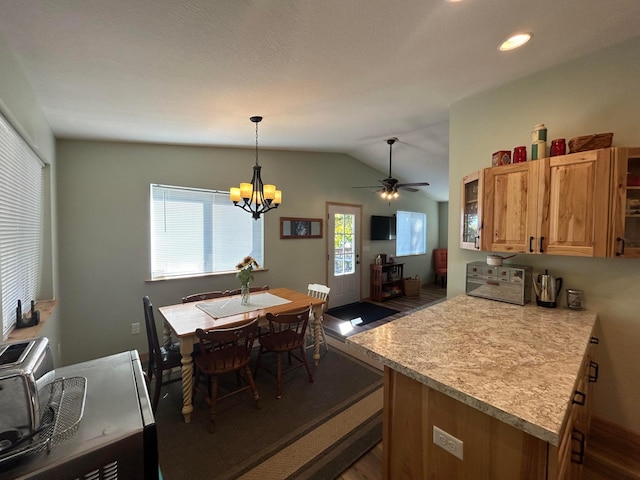 kitchen featuring ceiling fan with notable chandelier, lofted ceiling, pendant lighting, and dark wood-type flooring