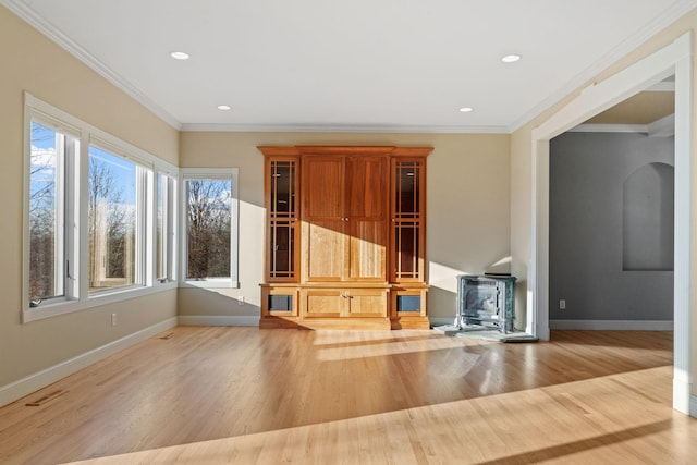 unfurnished living room featuring hardwood / wood-style flooring, ornamental molding, and a wood stove