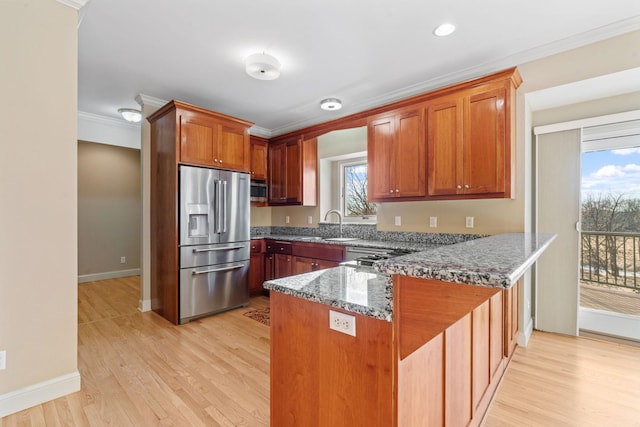 kitchen with crown molding, light hardwood / wood-style floors, a healthy amount of sunlight, stainless steel fridge with ice dispenser, and dark stone counters