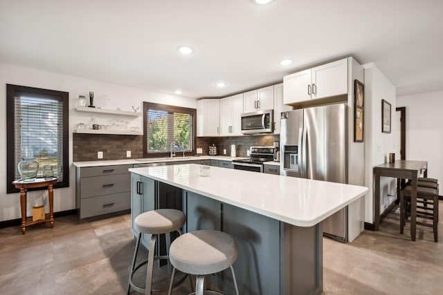 kitchen featuring gray cabinetry, a center island, a breakfast bar area, white cabinetry, and stainless steel appliances