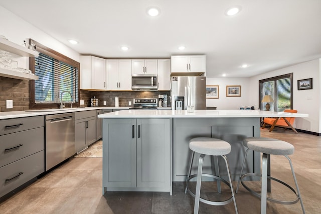 kitchen with white cabinets, appliances with stainless steel finishes, gray cabinets, and a kitchen island