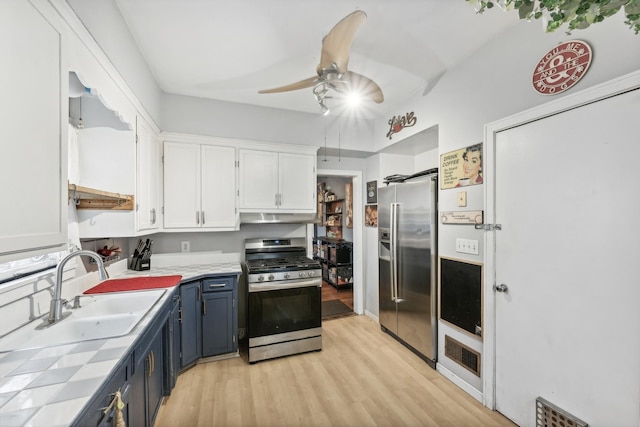 kitchen with blue cabinetry, sink, light hardwood / wood-style flooring, white cabinets, and appliances with stainless steel finishes