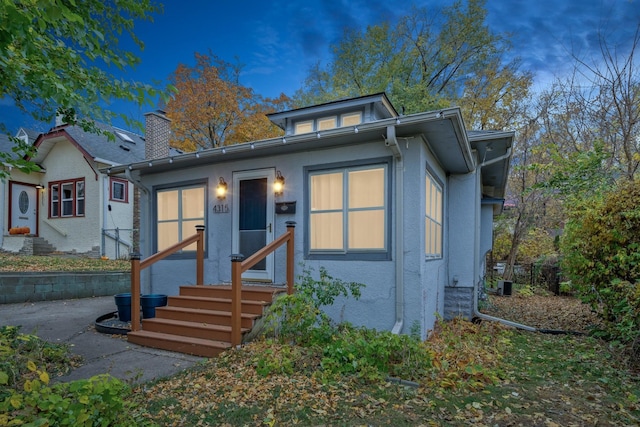 view of front of property featuring entry steps, a chimney, and stucco siding