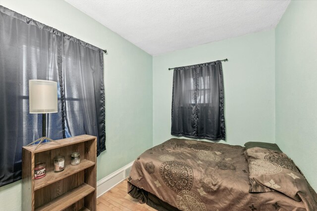 bedroom featuring a textured ceiling, wood finished floors, and baseboards