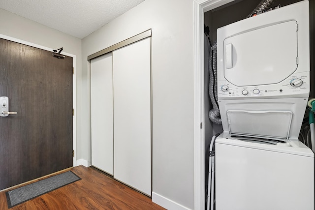 laundry room featuring dark hardwood / wood-style flooring, stacked washer and clothes dryer, and a textured ceiling