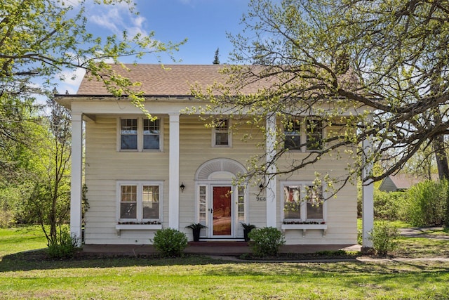 neoclassical / greek revival house with a front yard and roof with shingles