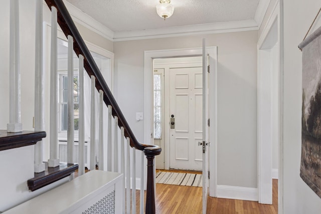 foyer entrance with light wood-style floors, stairs, baseboards, a textured ceiling, and crown molding